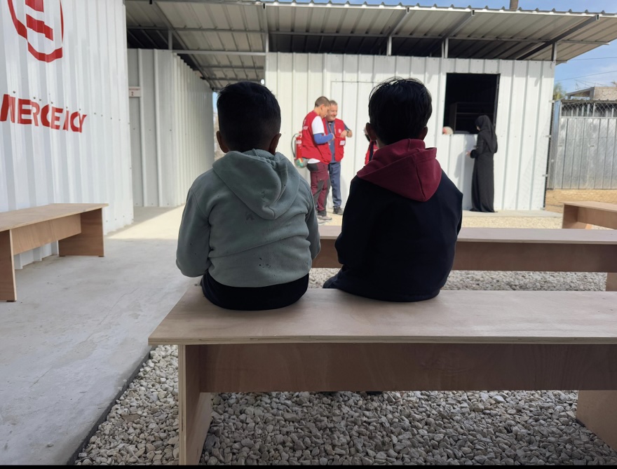 Nuova clinica, due bambini seduti osservano gli operatori - foto Archivio Emergency