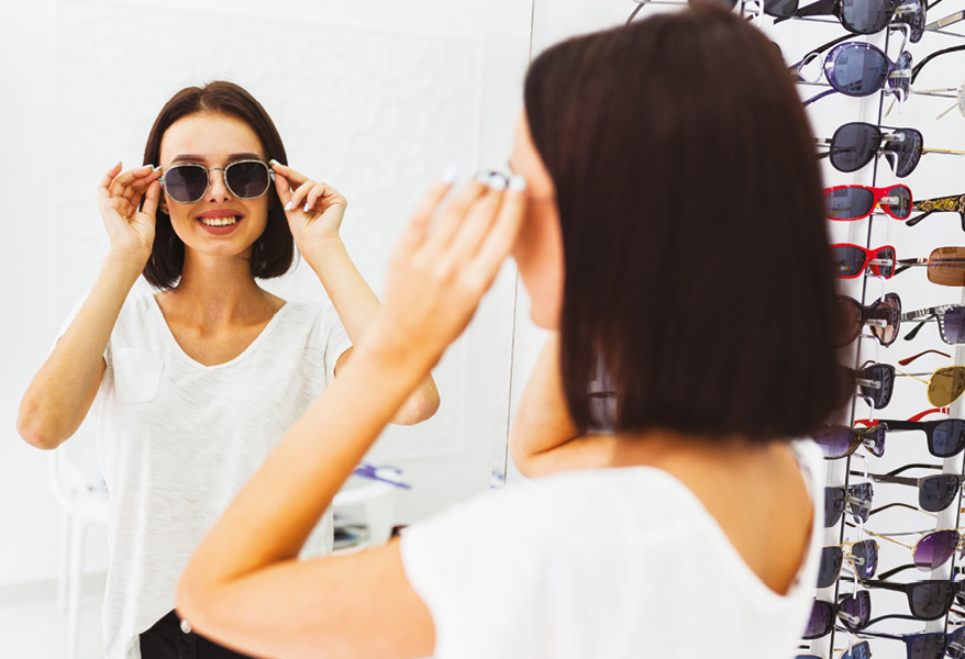 Giovane donna prova occhiali da sole in un negozio di ottica