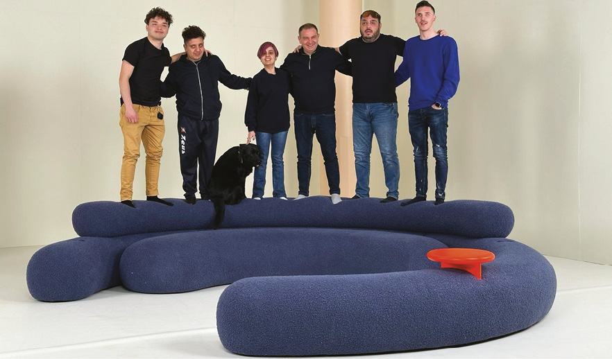 Project planner e allievi dell’Istituto F. Cavazza partecipanti al progetto, in piedi su un divano blu di design