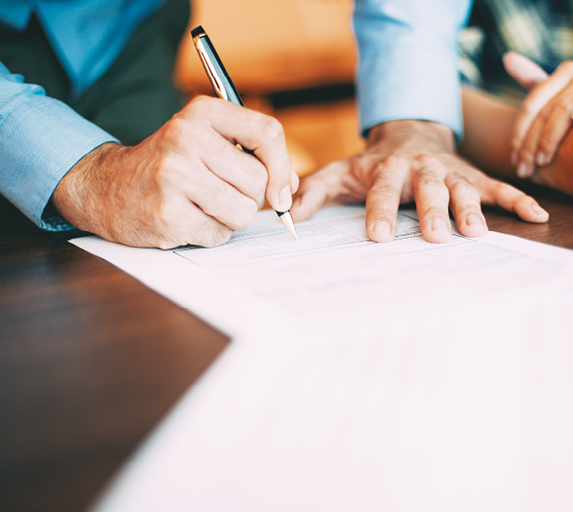 Close-up of hands signing a document - Photograph