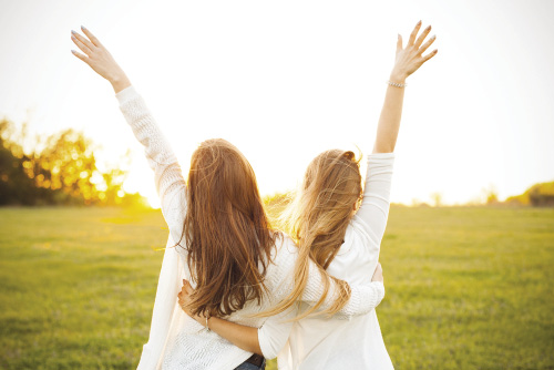 Due ragazze che si abbracciano guardando il sole