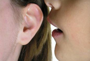 Picture of a person whispering in the ear of another person
